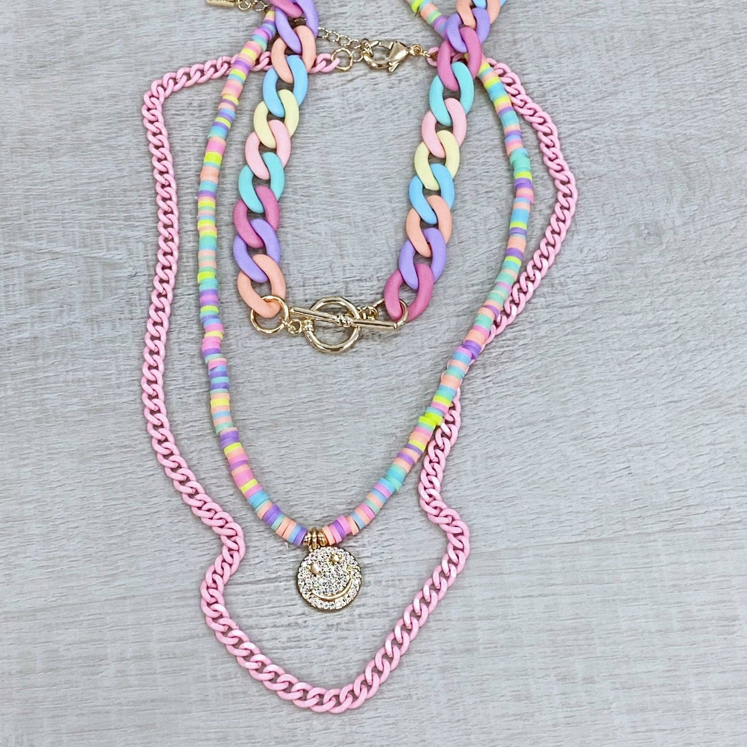 Multicolor spring choker handmade in acrylic in pastel color with gold-plated accessory combined with a puka pastel color necklace and a pick cuba chain by ISVI boutique Miami